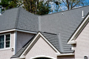Gray shingle roofing system on a tan house with white trim