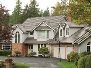 Two-story home with gray asphalt shingle roofing, white siding, and stone veneer